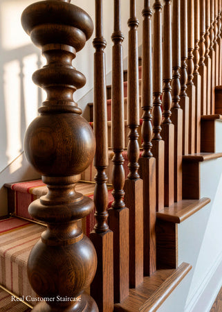 Close-up of a wooden staircase with turned balusters and a striped carpet runner, photographed in a real interior setting.