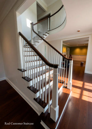 A modern staircase with dark wood treads and handrails, white spindles, and white wall trim in a bright home interior. A watermark in the lower-left corner reads 'Real Customer Staircase'.