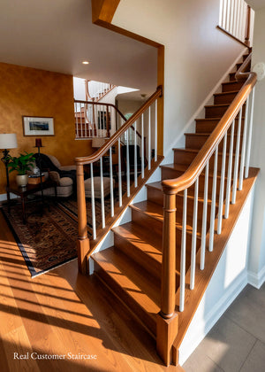 A warm-toned wooden staircase with white spindles in a residential home, showing hardwood floors, a living room on the left, and bright natural light streaming in from an open upper landing. inspiration