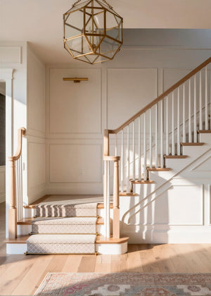 Staircase with wooden banisters and a geometric chandelier in a well-lit room.